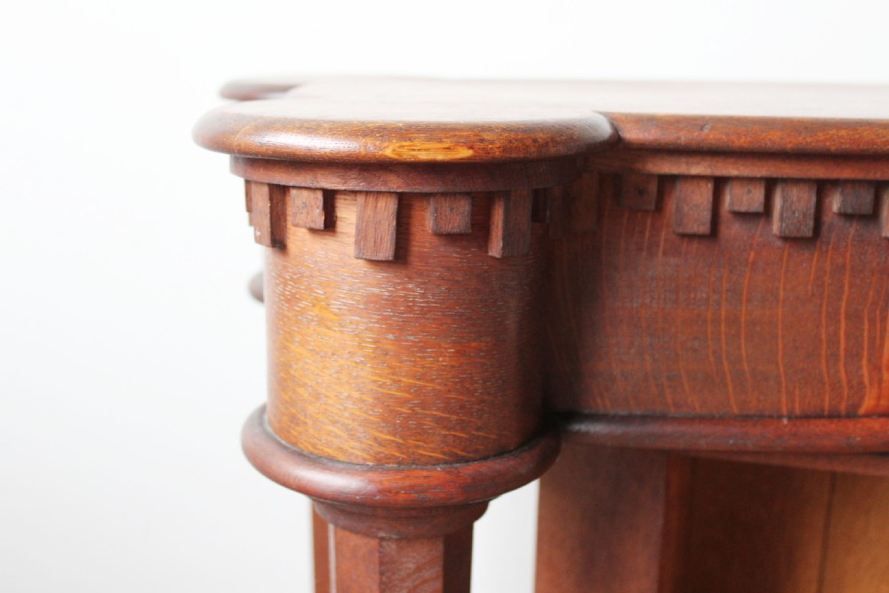 A warm brown oak Arts and Crafts occasional table featuring a dentil frieze and a central suspended hexagonal revolving cabinet. View IV
