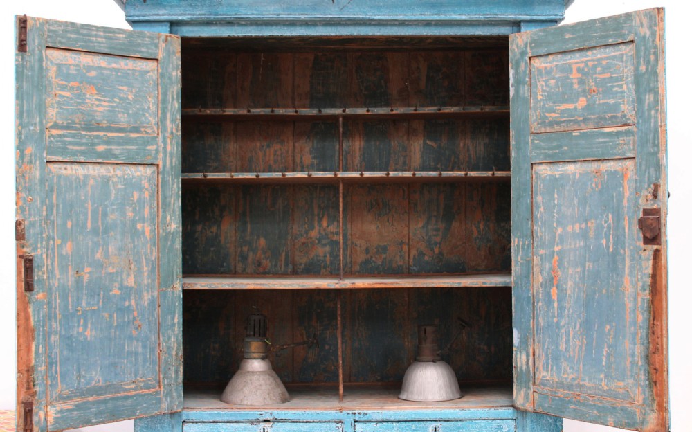 A 19th-century tall pine kitchen cupboard featuring a distressed blue painted finish, upper panelled doors, middle drawers, and lower cabinet doors. View V
