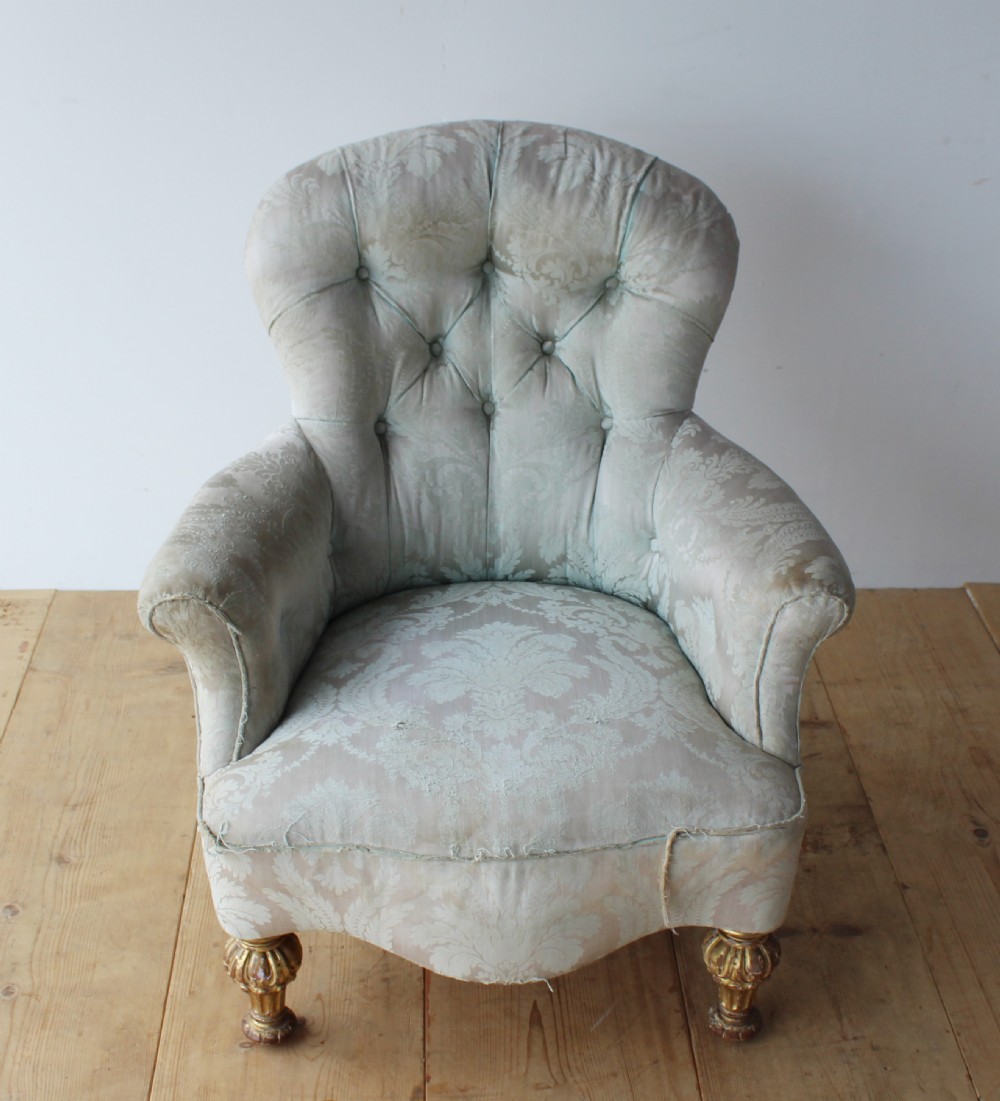 A 19th-century button-backed armchair upholstered in patterned pale sage damask fabric with rolled arms and turned gilded front legs. View II