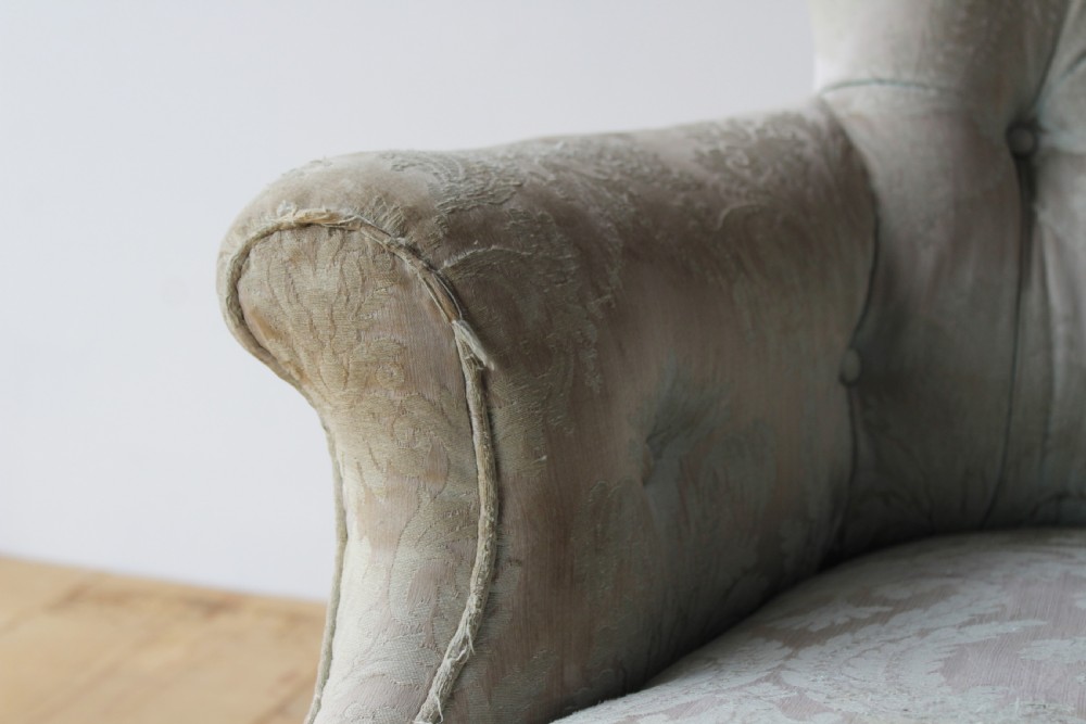 A 19th-century button-backed armchair upholstered in patterned pale sage damask fabric with rolled arms and turned gilded front legs. View III