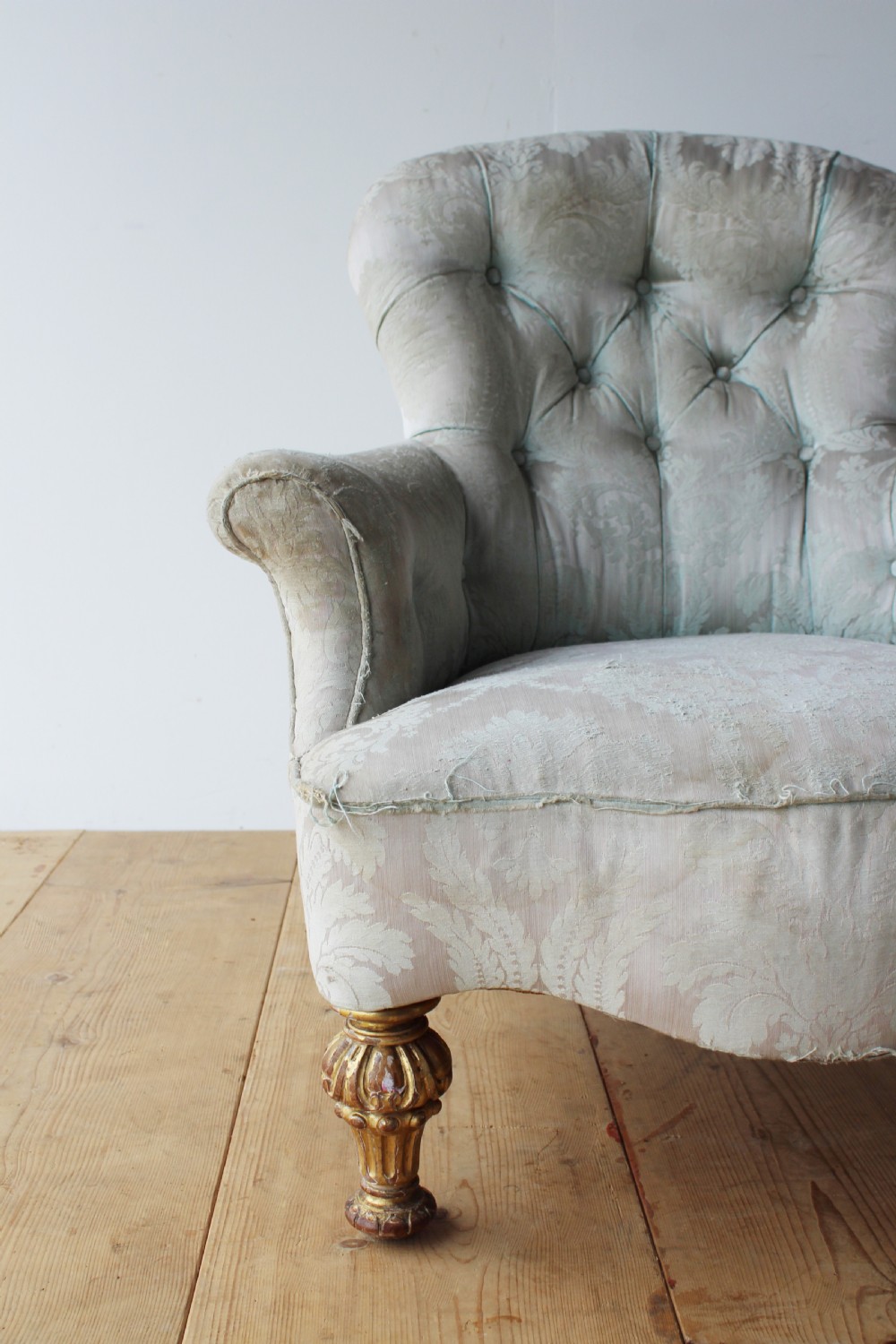 A 19th-century button-backed armchair upholstered in patterned pale sage damask fabric with rolled arms and turned gilded front legs. View IV