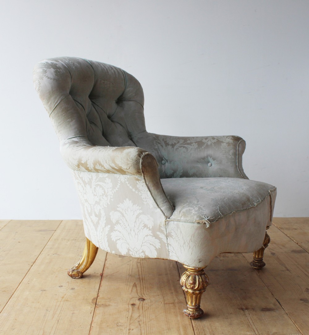 A 19th-century button-backed armchair upholstered in patterned pale sage damask fabric with rolled arms and turned gilded front legs. View V