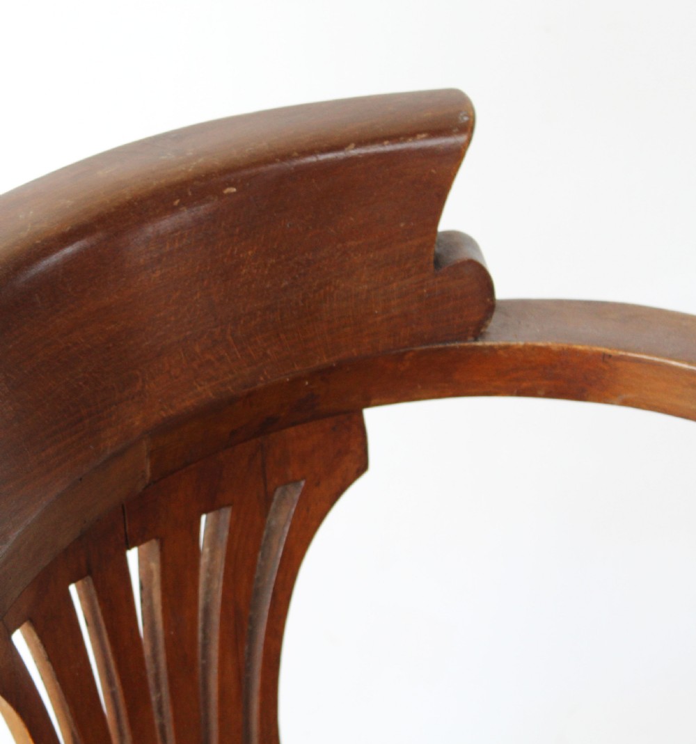 A set of six dark wooden captain armchairs featuring curved horseshoe backrests, slatted splats, and turned legs on a light timber floor. View IV