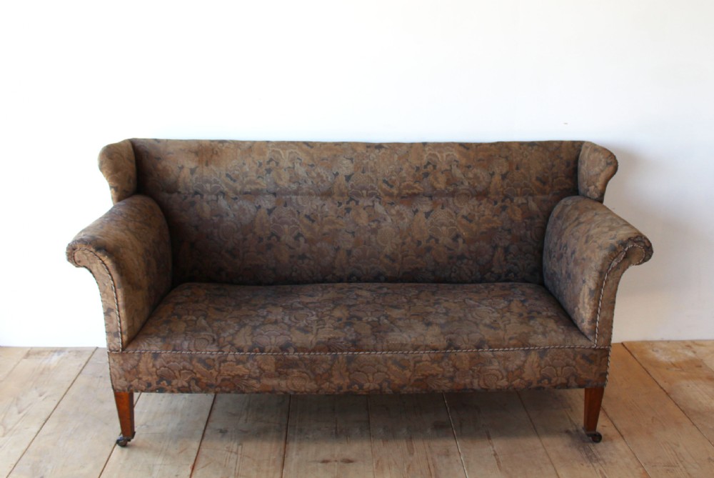 A nineteenth-century upholstered sofa featuring brown patterned tapestry fabric, scrolled arms, a high back, and tapered timber legs with brass castors. View II
