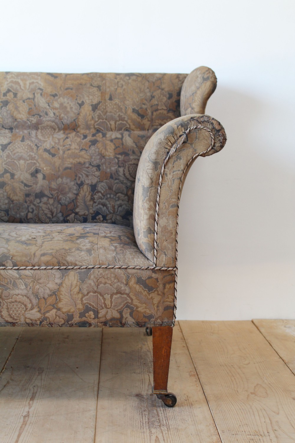 A nineteenth-century upholstered sofa featuring brown patterned tapestry fabric, scrolled arms, a high back, and tapered timber legs with brass castors. View III