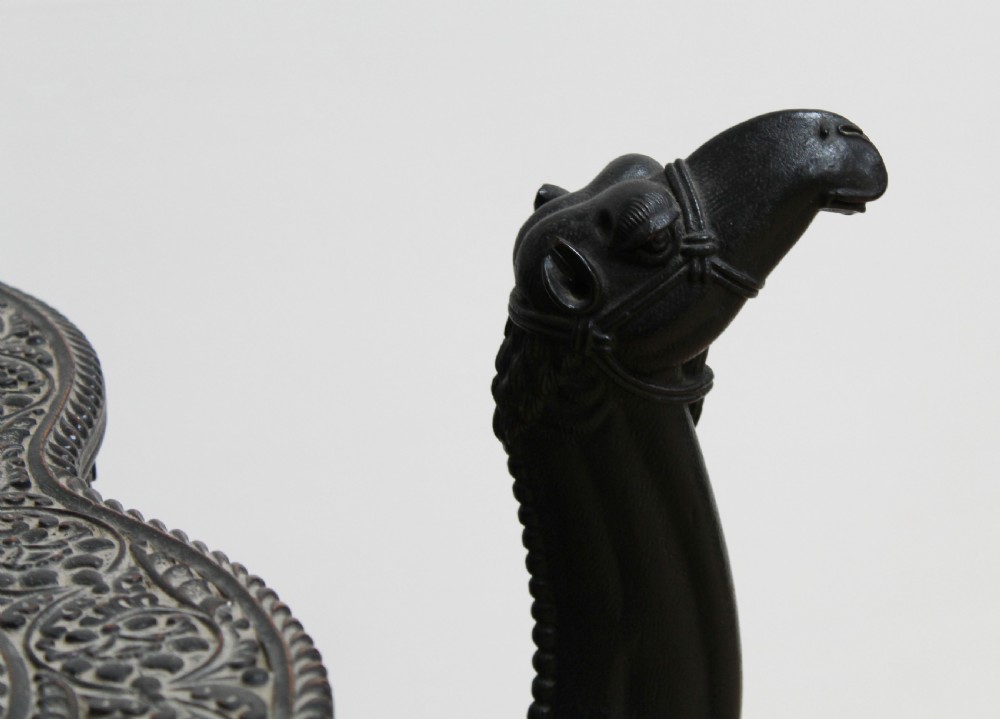 A dark carved wooden side table crafted in the form of a standing camel supporting a circular carved top on its saddle base. View V