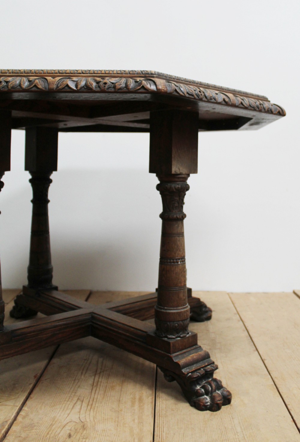 A 19th-century octagonal dark oak centre table with a carved foliate apron, turned columnar legs, an X-shaped stretcher, and carved paw feet. View II