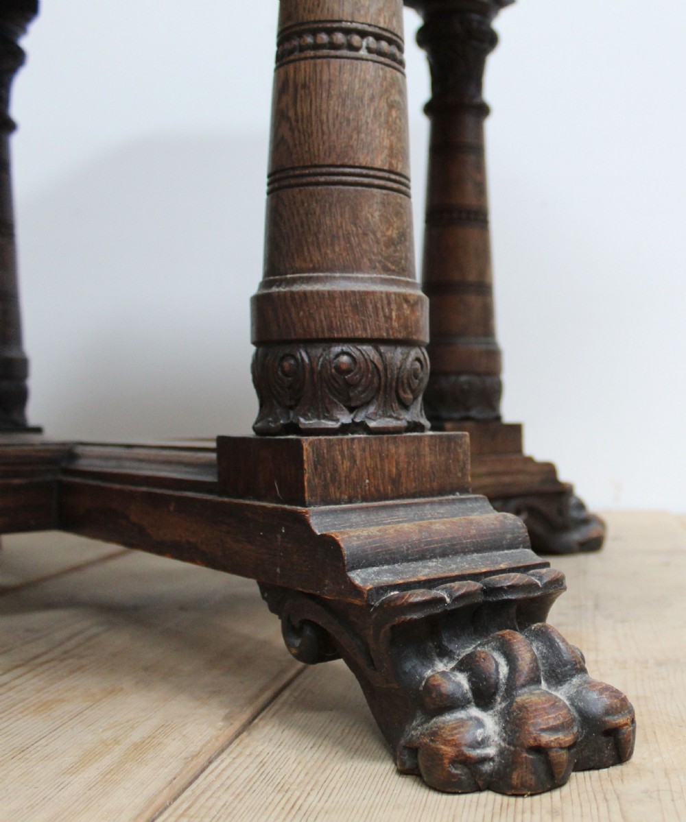 A 19th-century octagonal dark oak centre table with a carved foliate apron, turned columnar legs, an X-shaped stretcher, and carved paw feet. View III