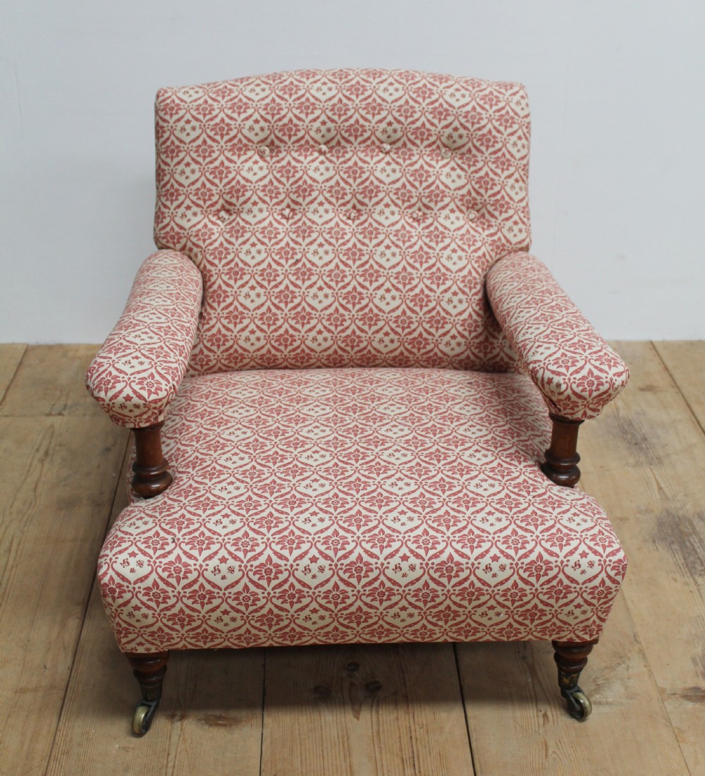 A low-seated Victorian upholstered armchair with patterned red and cream fabric, turned wooden arm supports, and brass castors. View III