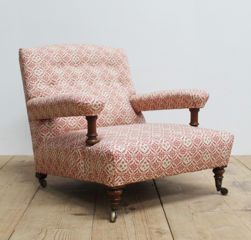 A low-seated Victorian upholstered armchair with patterned red and cream fabric, turned wooden arm supports, and brass castors. View IV