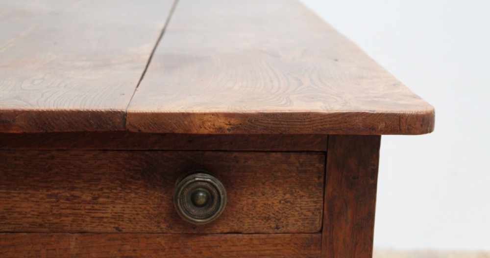 A 19th-century rustic wooden farmhouse dining table featuring a planked top, tapered square legs, and a single end drawer with wooden knobs. View V