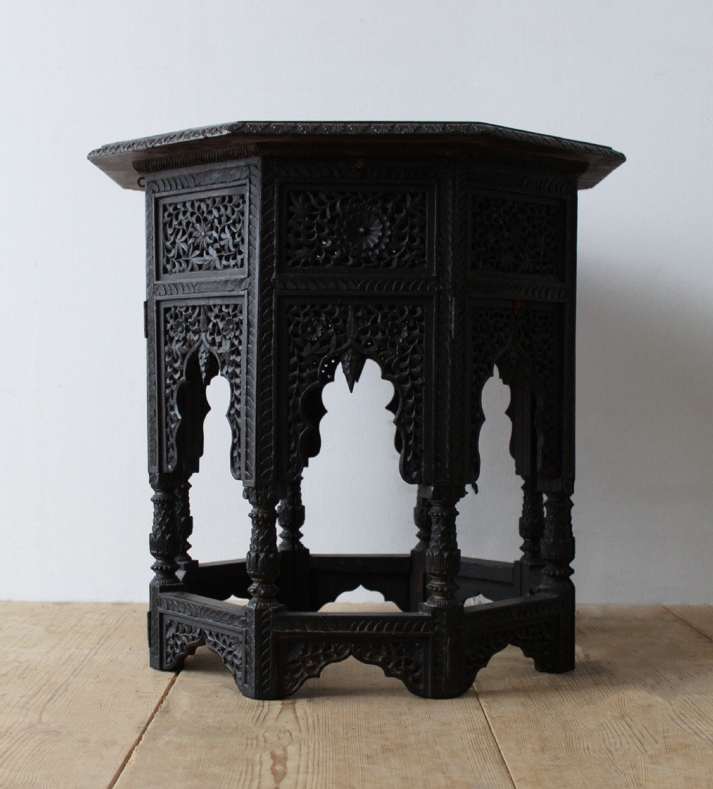 An octagonal dark hardwood side table featuring intricate openwork fretwork carving along the base and geometric borders surrounding a smooth central top. View IV