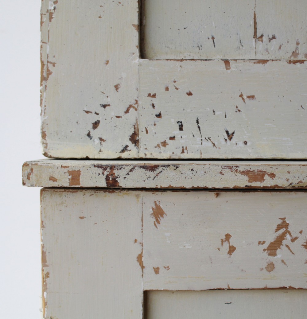 A tall 19th-century two-tier painted wooden linen cupboard with four panelled doors, a distressed off-white finish, turned wooden knobs, and brass keyhole escutcheons. View III