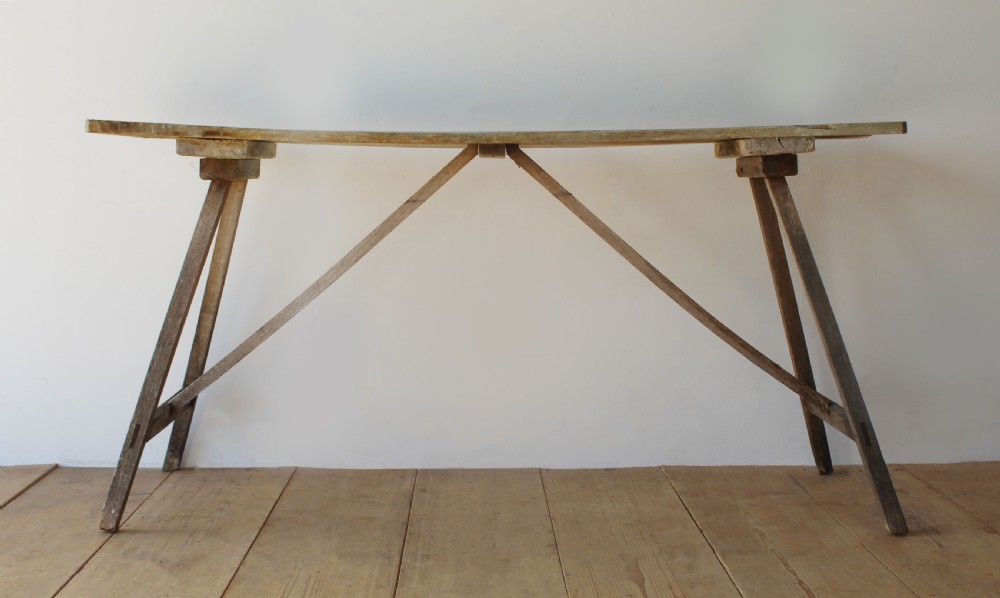 A late 19th-century rustic wooden wash table featuring splayed legs, diagonal cross bracing, and a weathered pine surface.
