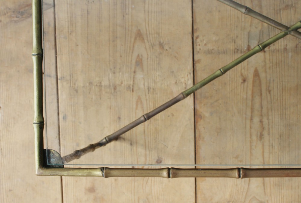 A rectangular coffee table featuring an aged brass frame designed with faux bamboo nodes, an X-shaped cross-stretcher, and a clear glass top. View III