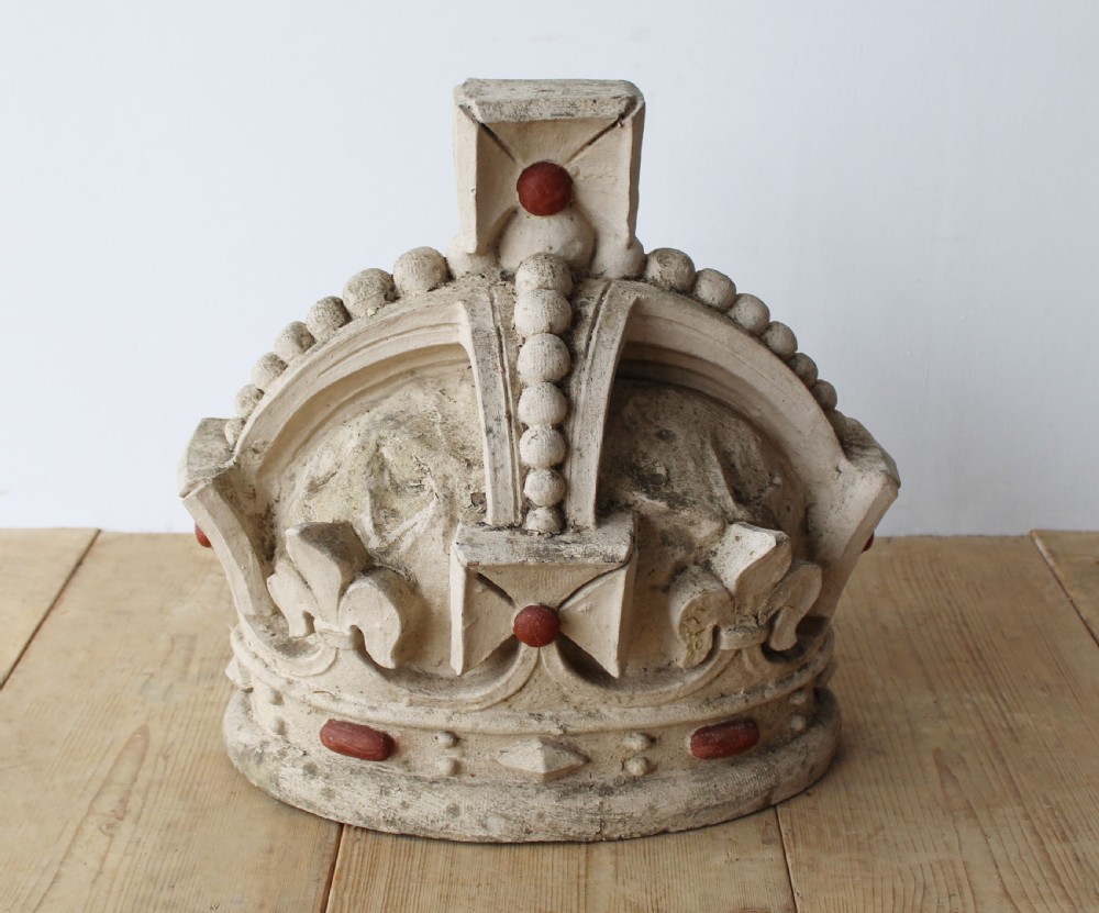 A large off-white carved composition stone crown sculpture featuring beadwork, fleur-de-lis motifs, and rounded red cabochon details.