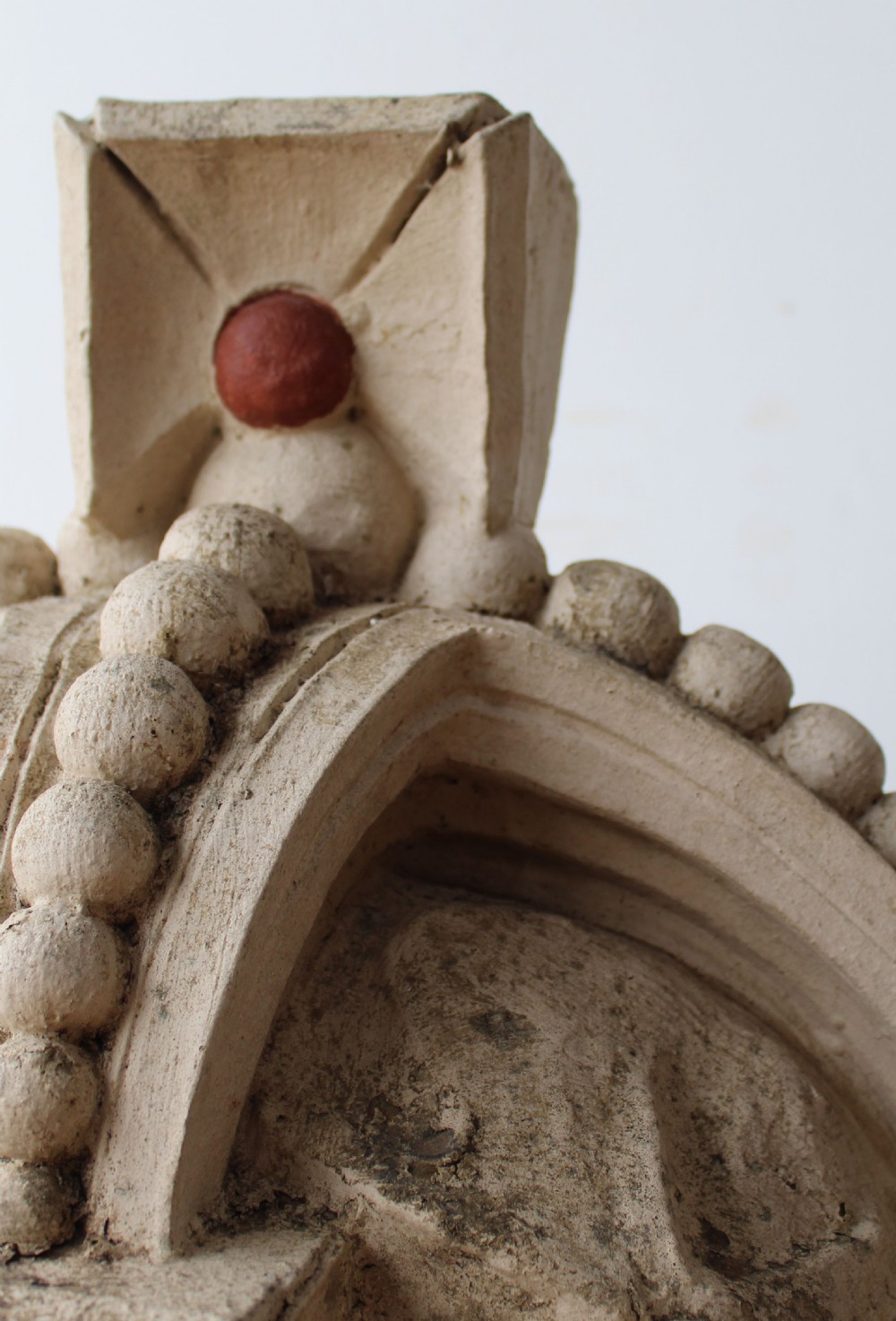 A large off-white carved composition stone crown sculpture featuring beadwork, fleur-de-lis motifs, and rounded red cabochon details. View III