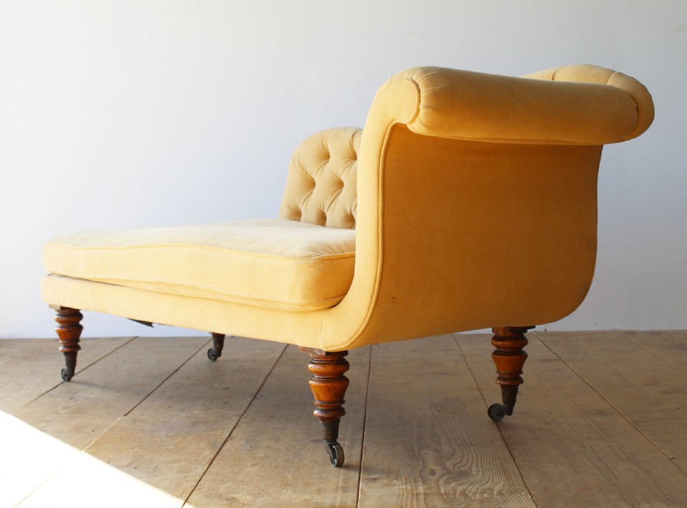 An early nineteenth-century chaise longue upholstered in mustard yellow velvet featuring deep-buttoned tufting, a scrolled arm, and turned wooden legs on castors. View III