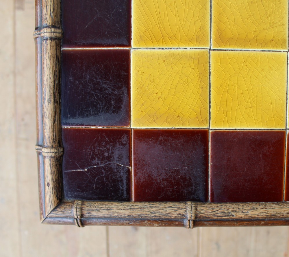 A late 19th-century dark bamboo lamp table featuring a square inset top lined with yellow and dark brown ceramic tiles and cross-braced legs. View III