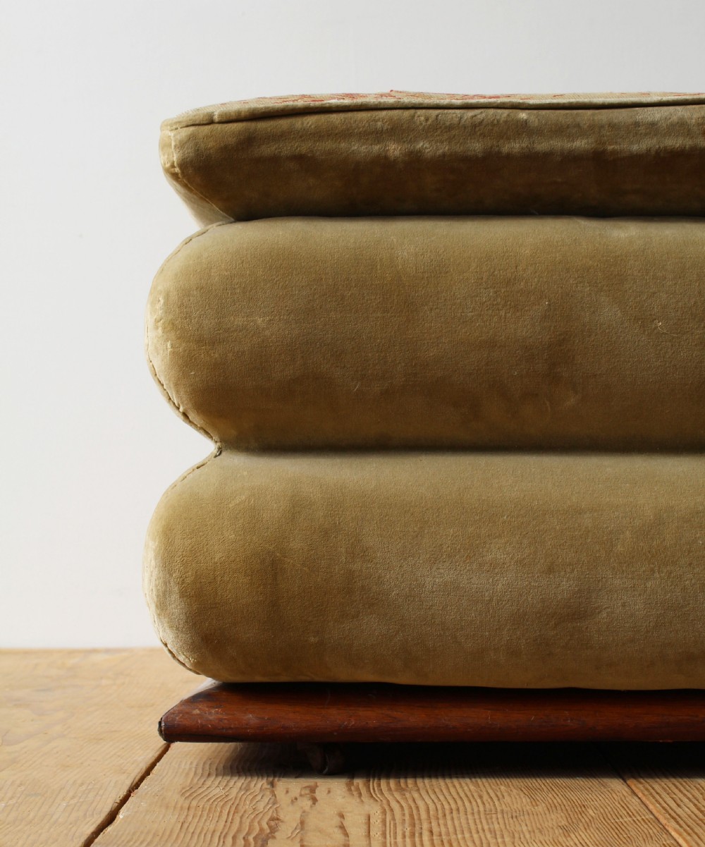 A large 19th-century tiered country ottoman with gold-green velvet upholstery, floral needlepoint top, and a wooden plinth base. View III