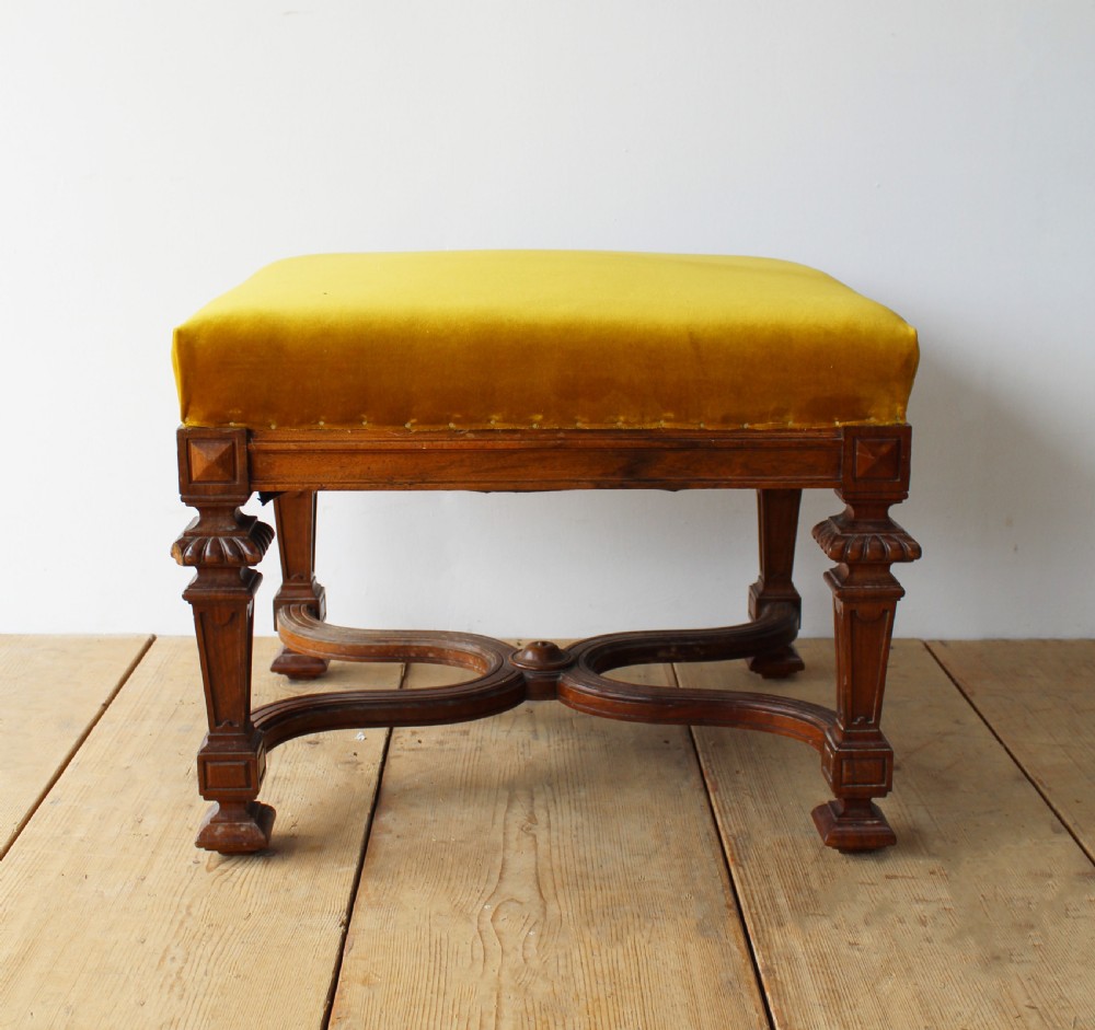 A pair of square upholstered stools featuring mustard yellow velvet seats and carved dark wood legs connected by curved cross-stretchers. View III
