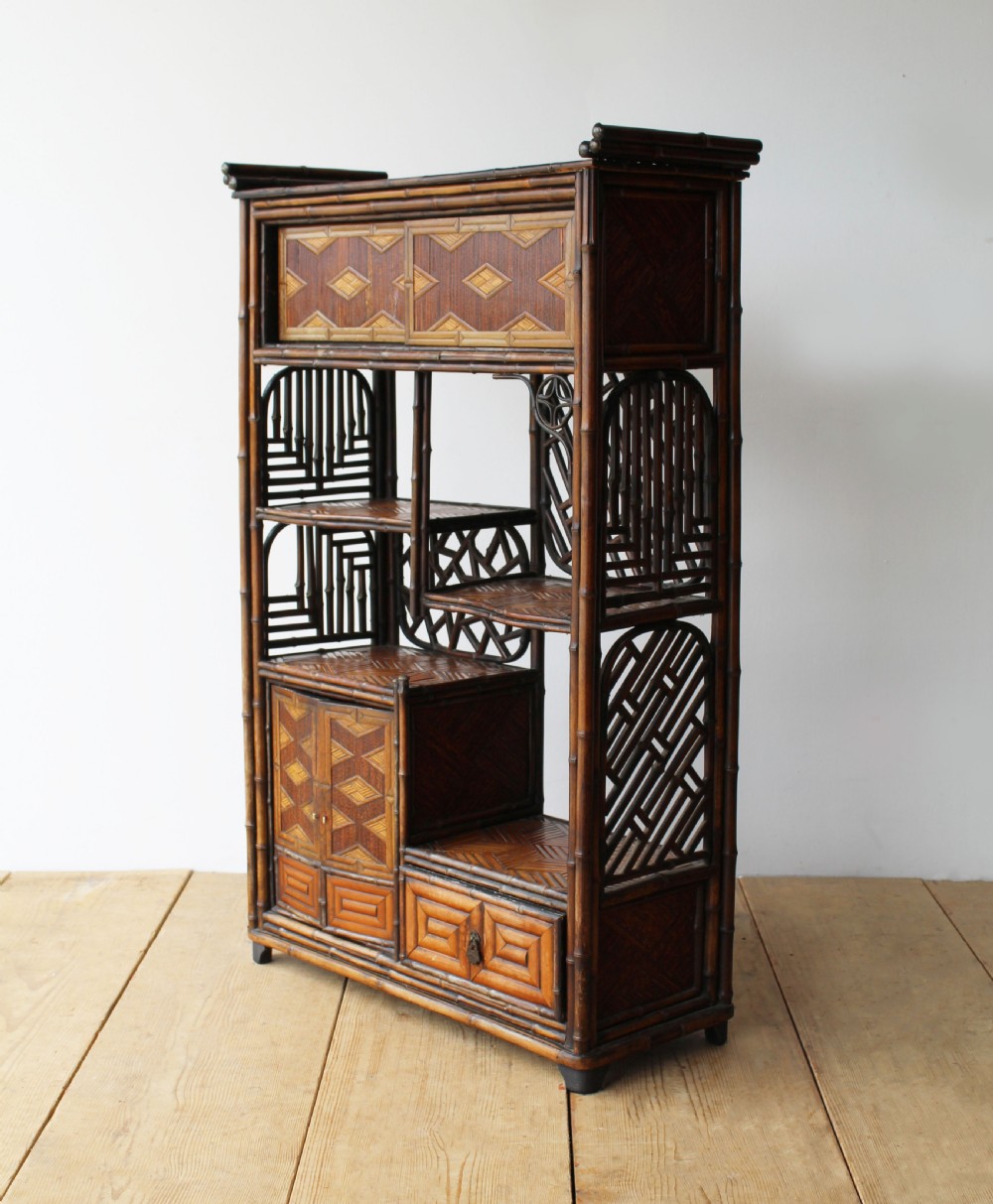 A late 19th-century Victorian bamboo display cabinet featuring asymmetrical shelving, geometric straw parquetry cupboard doors, and decorative lattice back panels. View IV