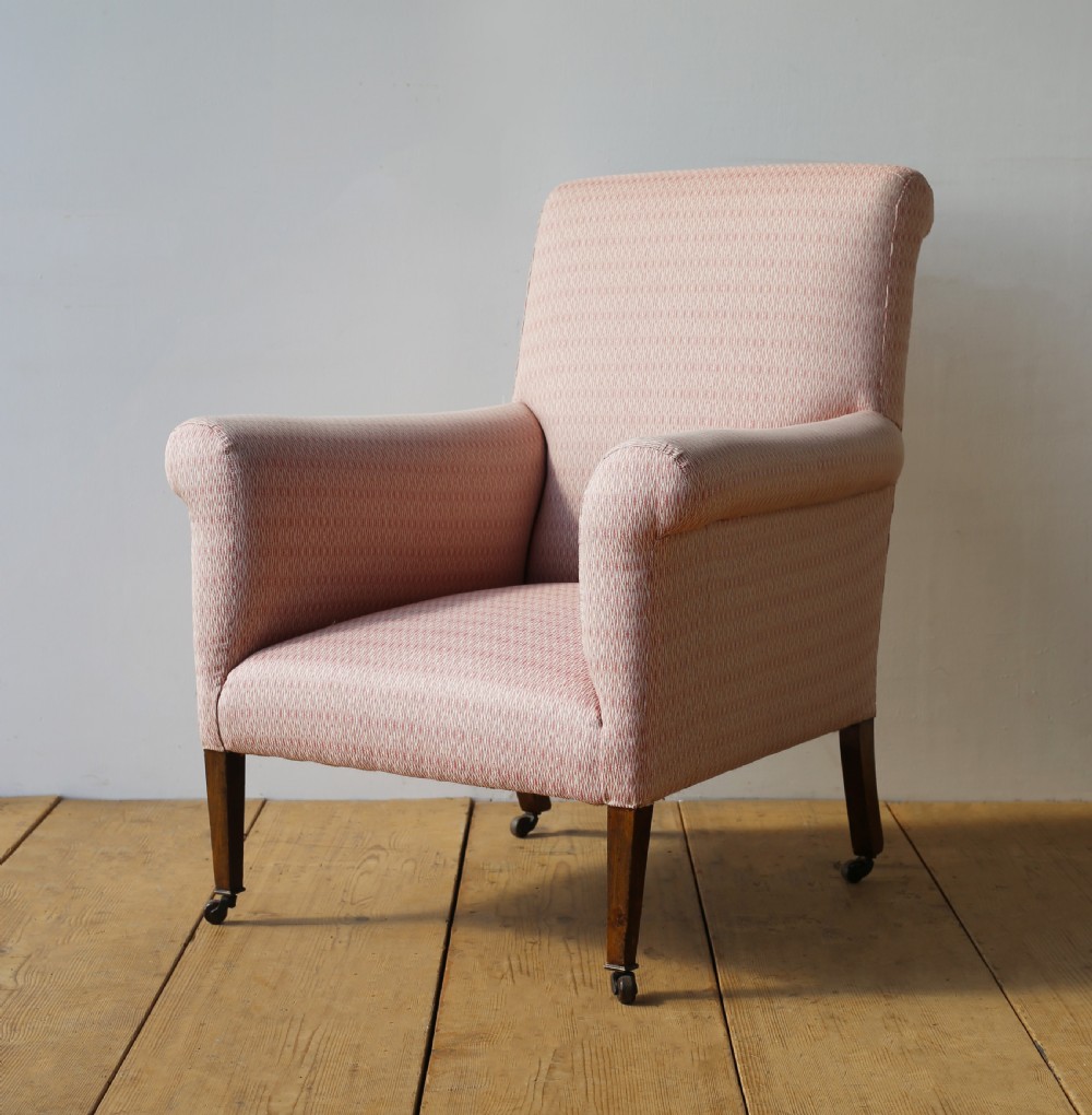 A 19th-century upholstered armchair featuring dusky pink patterned fabric, scrolled arms, square tapered front legs, and brass castors. View III