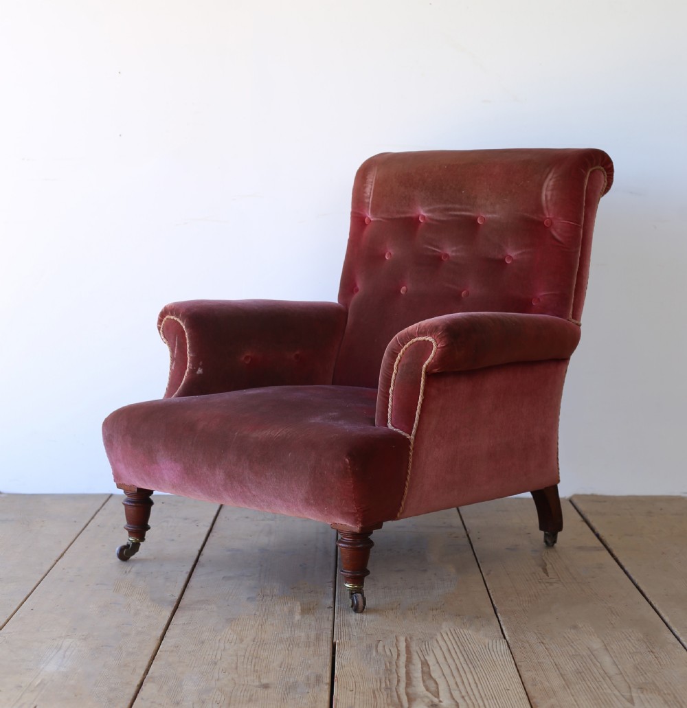 A 19th-century Victorian armchair upholstered in deep red velvet, featuring a buttoned backrest, scrolled arms with braid trim, and turned wooden front legs on brass castors. View III