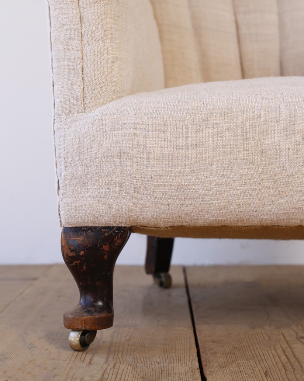 A high-backed 19th-century barrel back armchair with vertical fluting, upholstered in neutral off-white fabric on turned timber legs with brass castors. View II