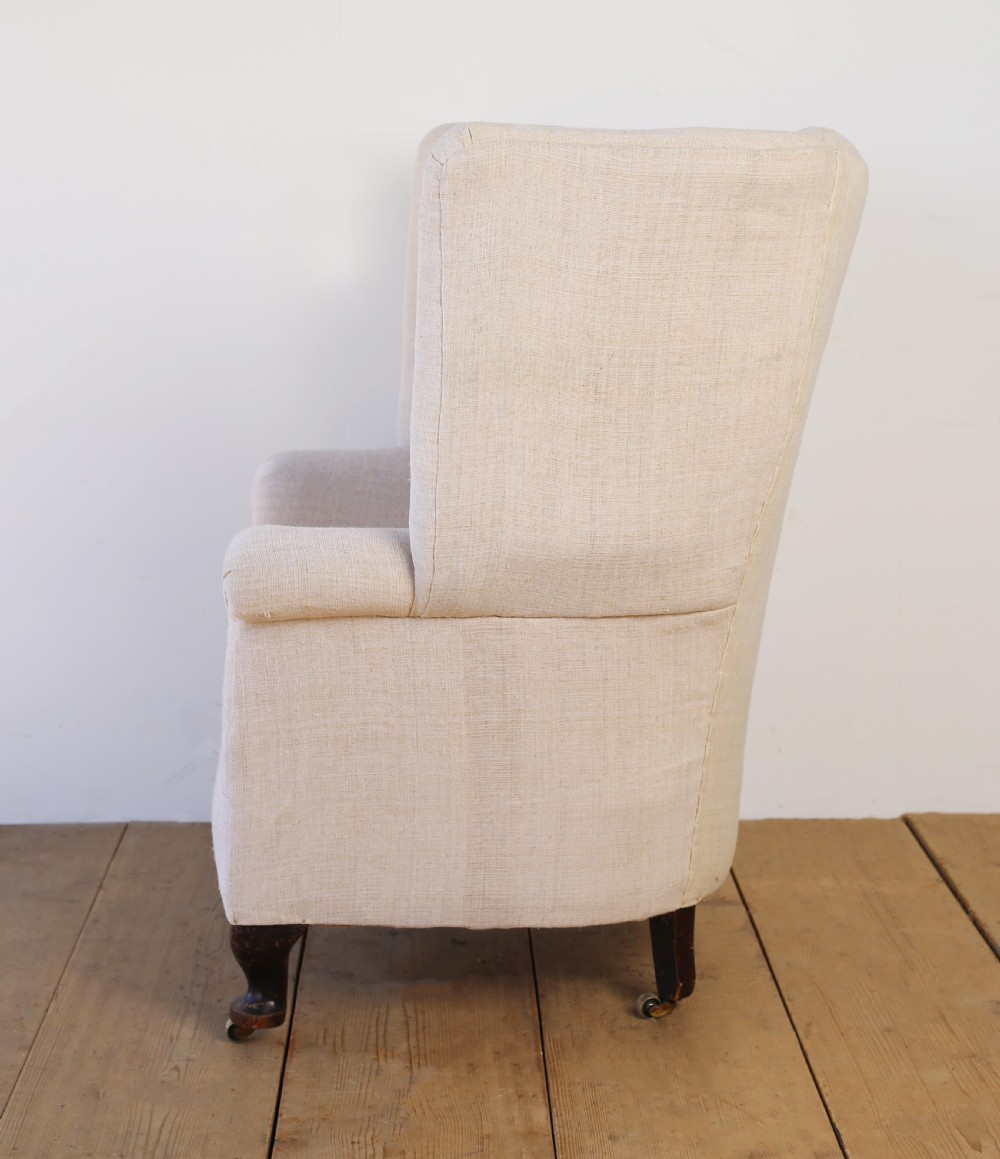 A high-backed 19th-century barrel back armchair with vertical fluting, upholstered in neutral off-white fabric on turned timber legs with brass castors. View IV