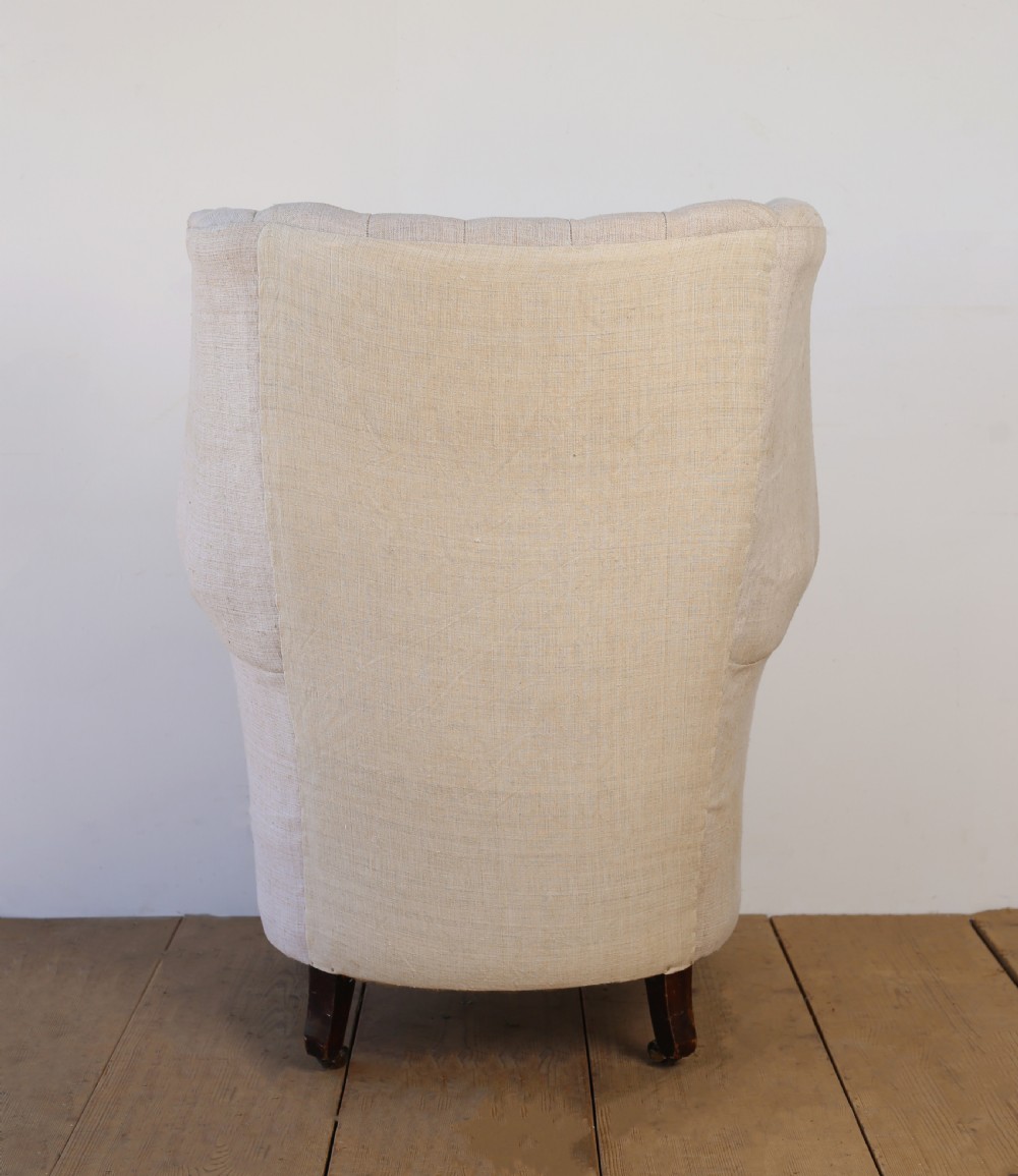 A high-backed 19th-century barrel back armchair with vertical fluting, upholstered in neutral off-white fabric on turned timber legs with brass castors. View V