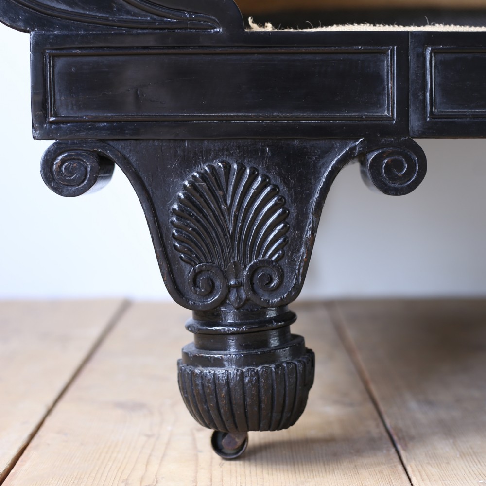 A 19th-century Regency sofa featuring an ebonised dark wooden frame with scrolled arms, carved feet, and natural hessian lining. View III