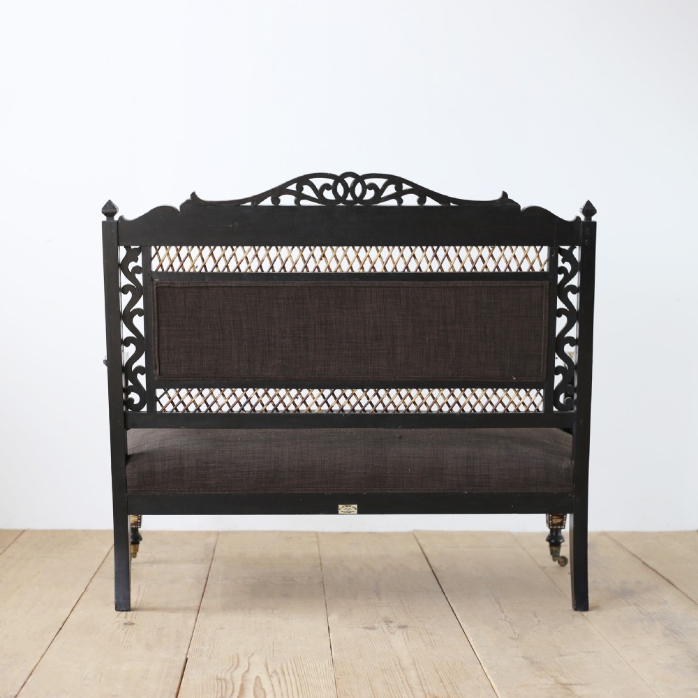 A nineteenth-century Anglo-Indian porcupine quill settee crafted from dark ebony wood with geometric bone dot inlay and dark brown fabric upholstery. View V