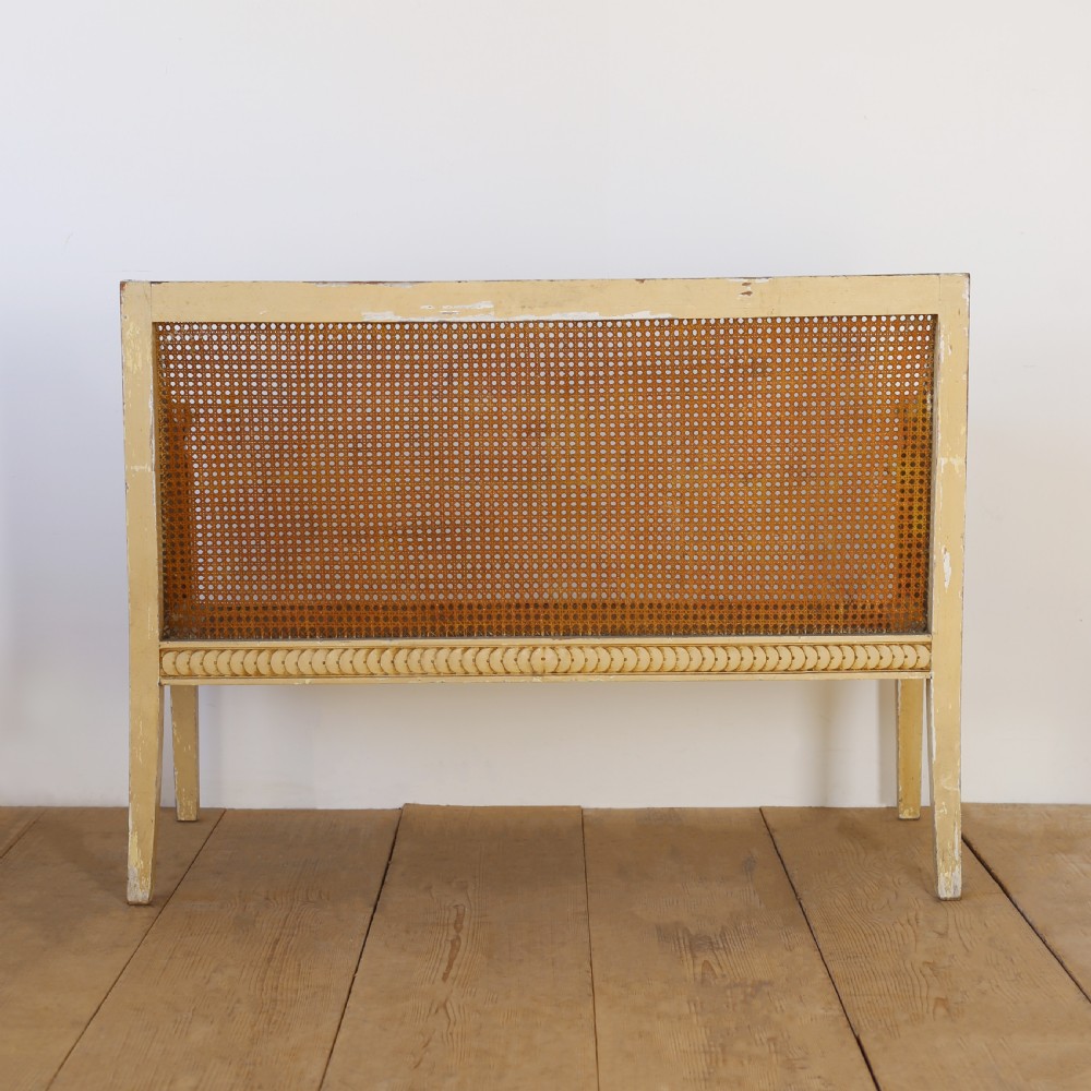A cream painted wooden settee with a carved guilloche motif frame and woven cane back, side, and seat panels. View IV