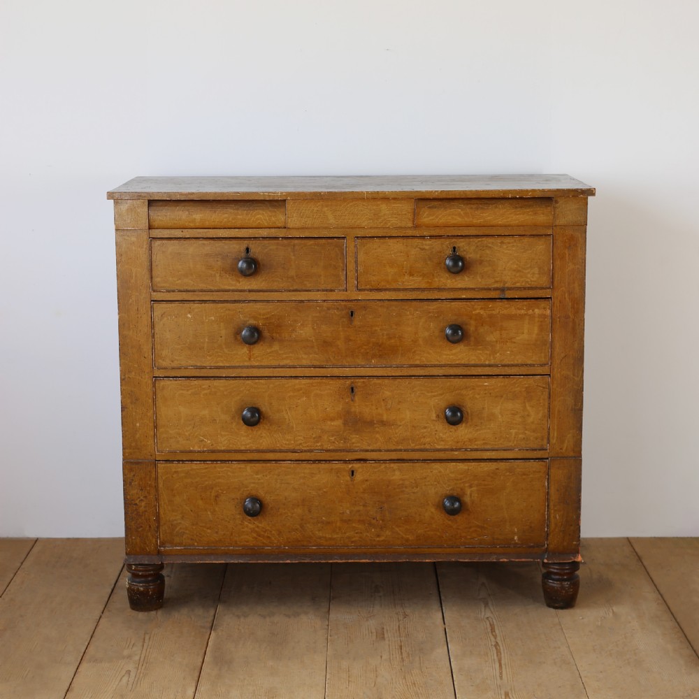 A 19th-century timber chest of drawers with turned wooden knobs and short turned feet.