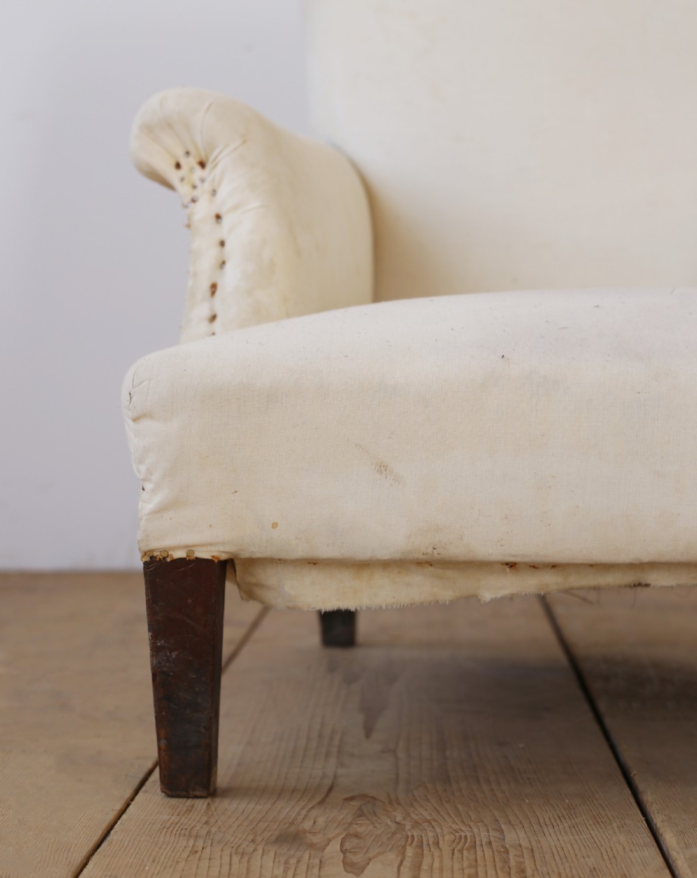 A 19th-century Howard style armchair upholstered in off-white calico fabric with exposed dark wood tapered front legs and brass studding along the scrolled arm fronts. View II