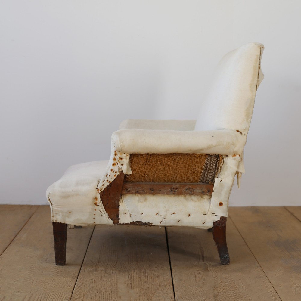 A 19th-century Howard style armchair upholstered in off-white calico fabric with exposed dark wood tapered front legs and brass studding along the scrolled arm fronts. View IV