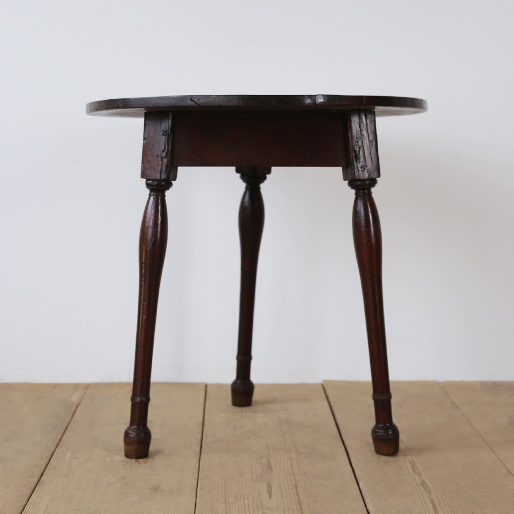 A dark oak 17th-century cricket table featuring a circular plank top and three turned legs. View II
