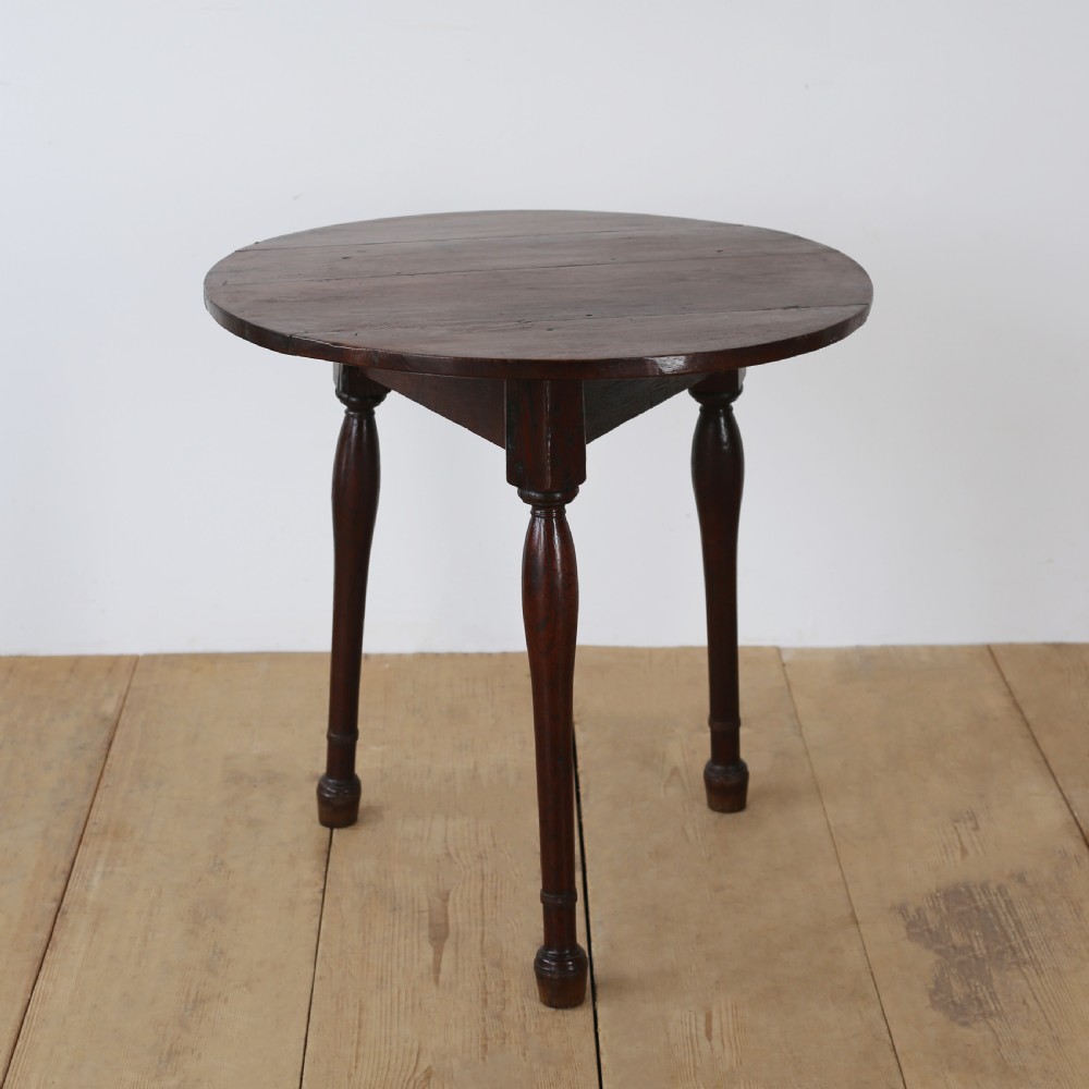 A dark oak 17th-century cricket table featuring a circular plank top and three turned legs. View III