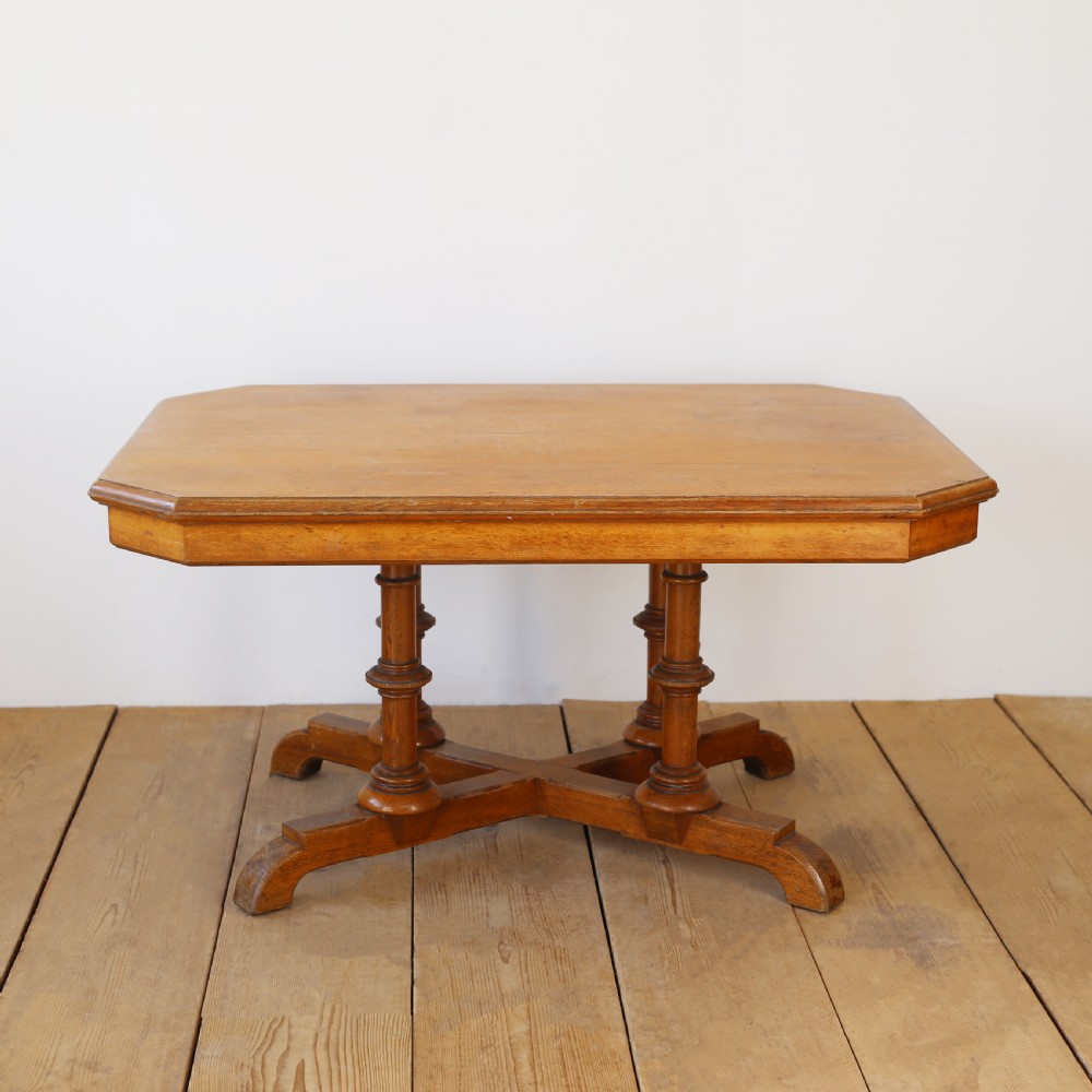 A 19th-century oak centre table featuring a canted-corner top supported by turned pillars and an X-shaped cross-stretcher base.
