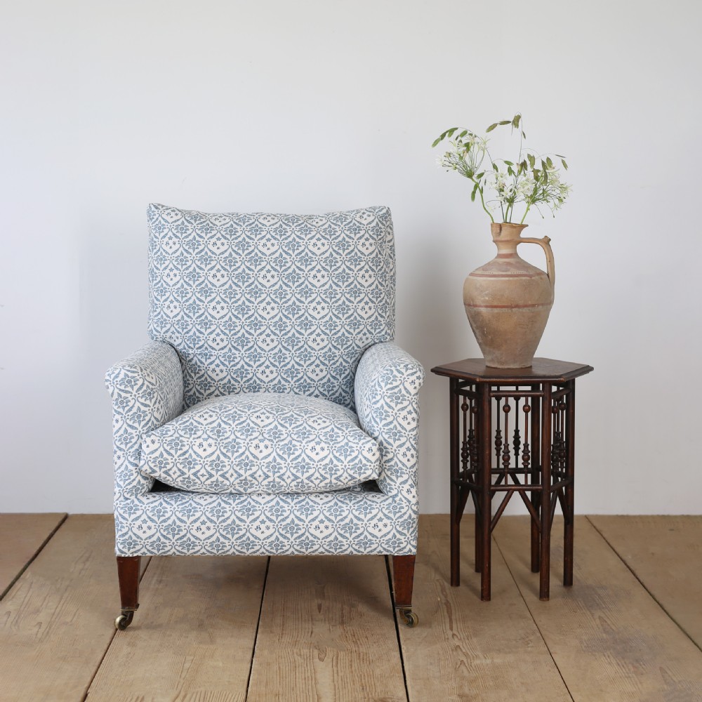 A Victorian upholstered armchair featuring a blue and white printed fabric, turned wooden front legs, and brass castors. View III
