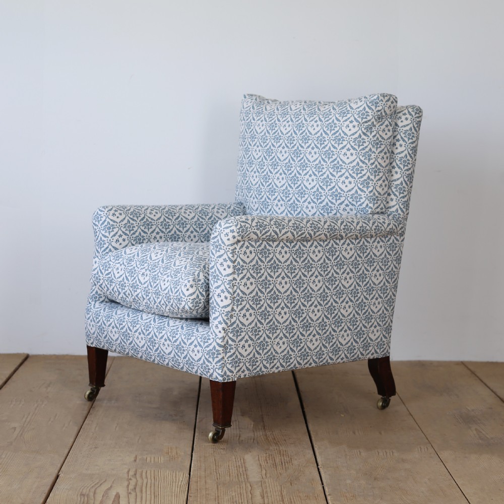 A Victorian upholstered armchair featuring a blue and white printed fabric, turned wooden front legs, and brass castors. View IV