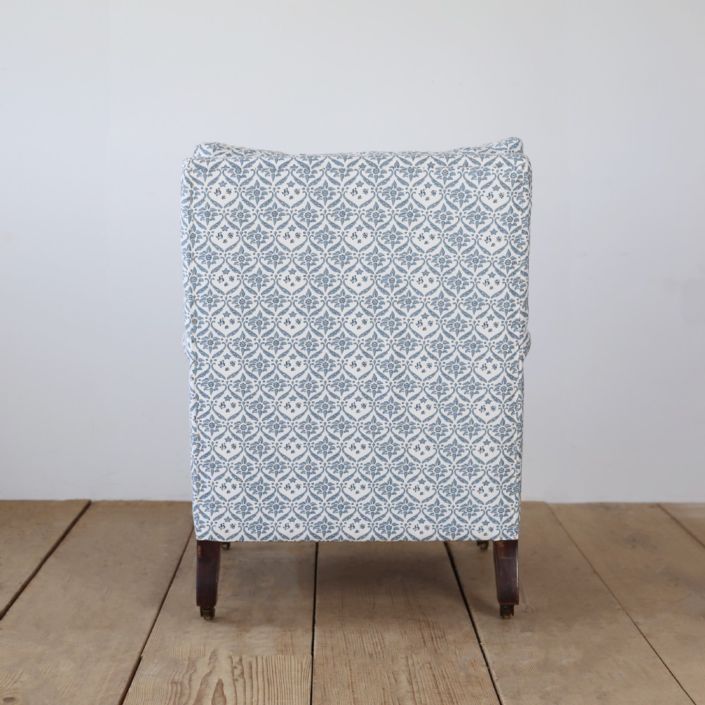 A Victorian upholstered armchair featuring a blue and white printed fabric, turned wooden front legs, and brass castors. View V