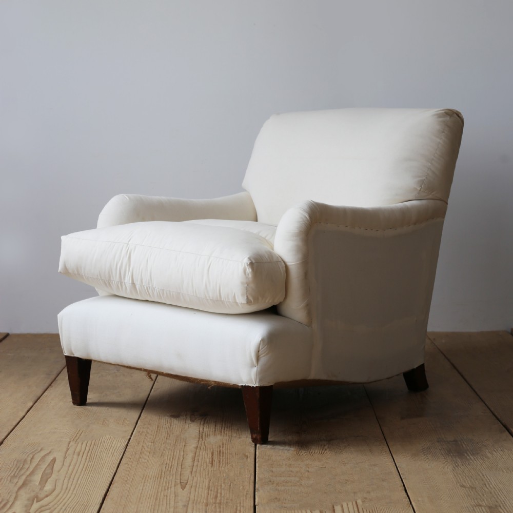 A cream calico upholstered Howard style armchair with a deep feather seat cushion, low rolled arms, and tapered dark wood legs. View III