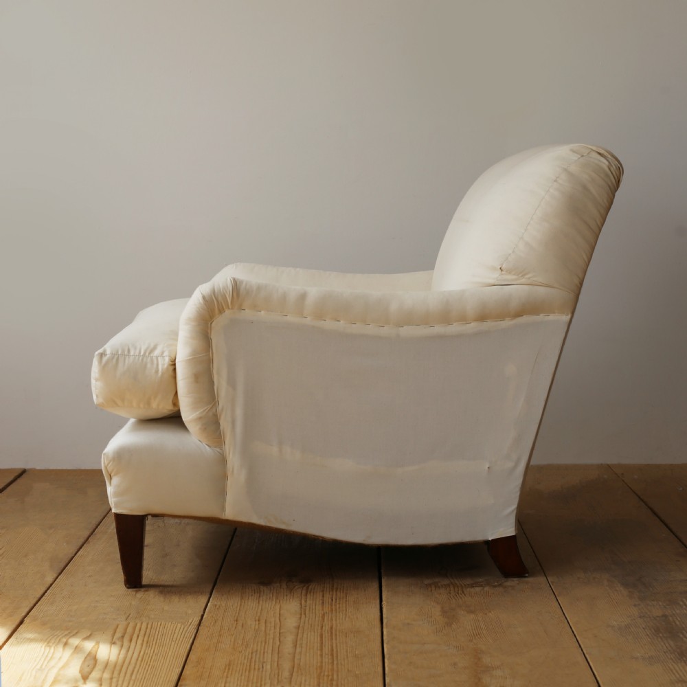 A cream calico upholstered Howard style armchair with a deep feather seat cushion, low rolled arms, and tapered dark wood legs. View IV