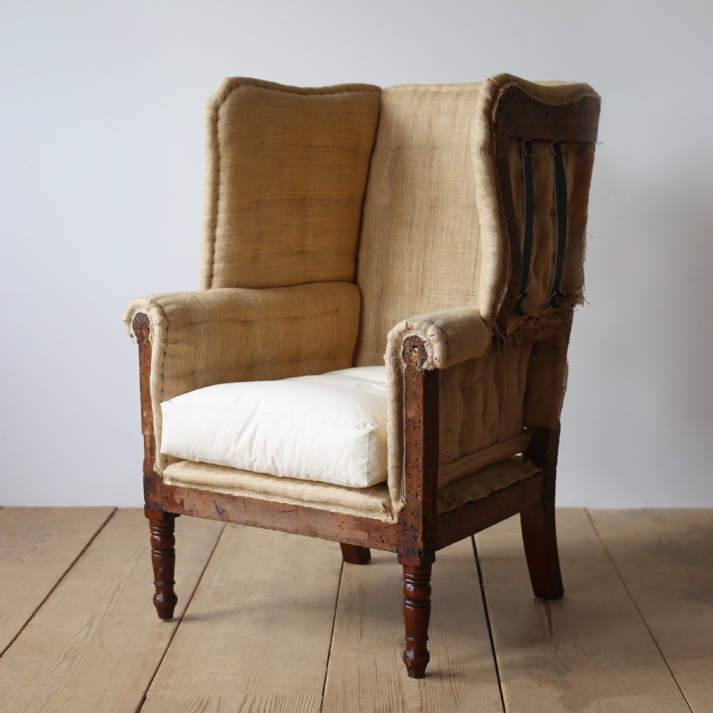 A 19th century wingback armchair presented in hessian upholstery with dark turned front legs and a off-white cushion. View III