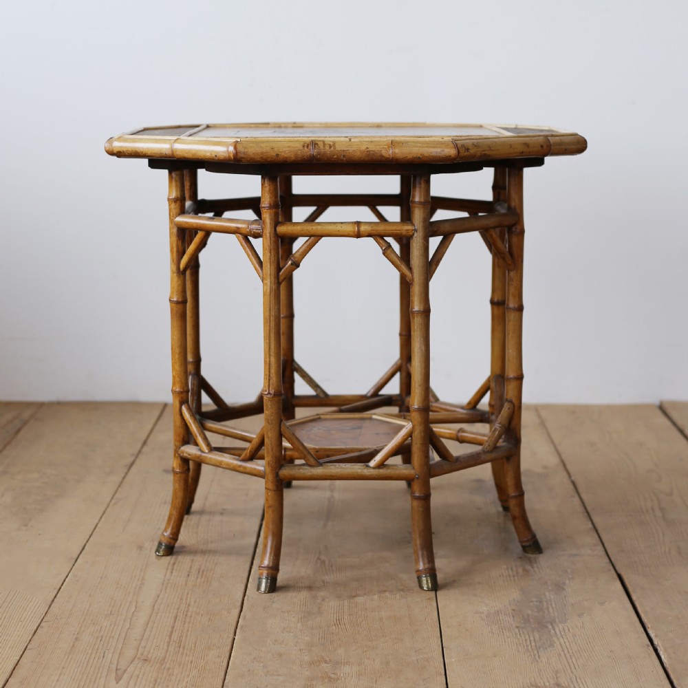 A nineteenth-century hexagonal bamboo centre table featuring bent bamboo legs, angled stretchers, a lower tier, and brass feet caps.