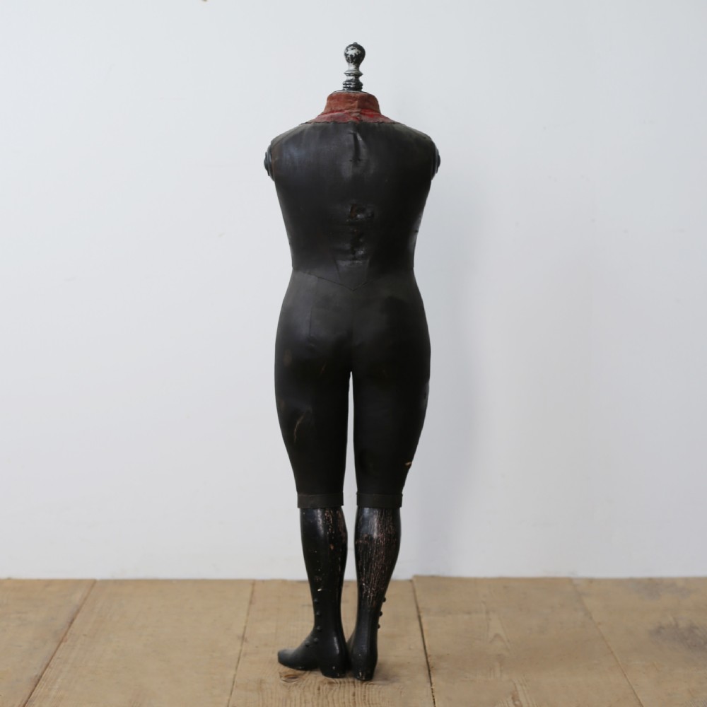 A 19th-century full-body standing tailor mannequin featuring a dark grey body with a contrasting reddish fabric chest insert and a turned top finial. View II