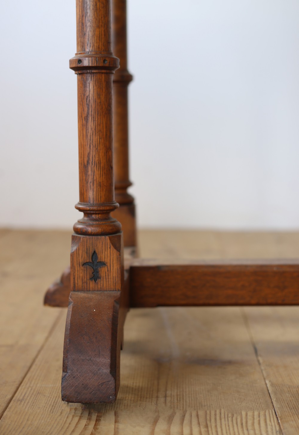 A 19th-century Gothic Revival oak writing table featuring turned columnar legs, a crenellated apron detail, and a low cross-stretcher. View II