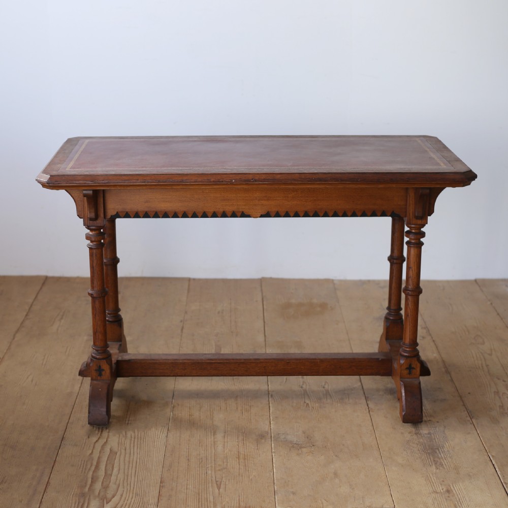 A 19th-century Gothic Revival oak writing table featuring turned columnar legs, a crenellated apron detail, and a low cross-stretcher. View IV
